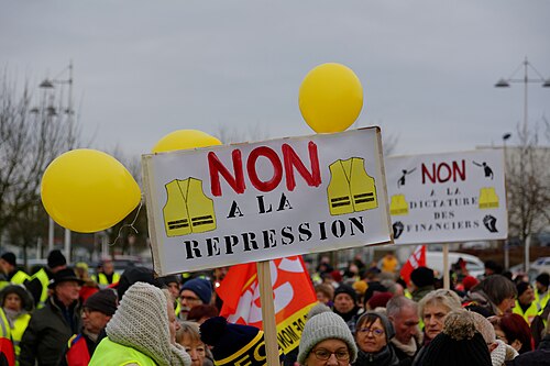 Pancartes « Non à la répression » et ballons jaunes dans un cortège.