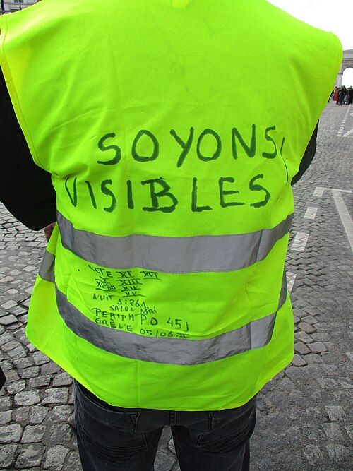 Dos d'un gilet jaune sur lequel est écrit au feutre « Soyons visibles ».